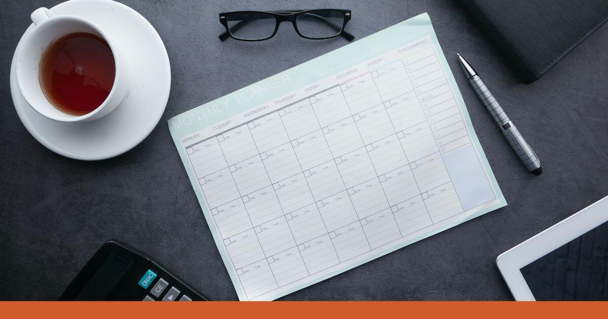 Auf einem Schreibtisch liegt ein Kalender ohne Termine und weitere Gegenstände aus dem Büroalltag